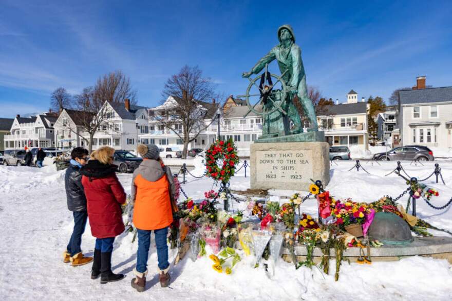 Jane Asaro Hartson, Patricia McGrath and Diana Taylor stand to honor the memory of the crew of the Lily Jean at the Fisherman’s Memorial in Gloucester on Monday. (Jesse Costa/WBUR)