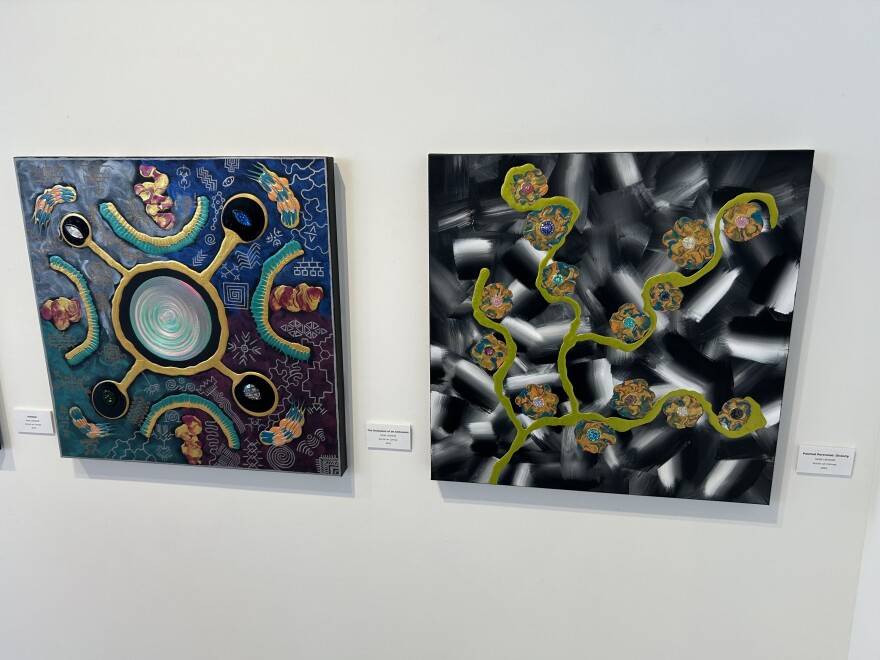 Paintings in black, white, yellow, blue, and orange on a white wall.