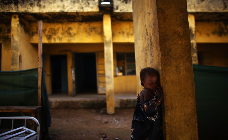 Aishsa Yusufa stands against a pillar outside the Doctors Without Borders ward in Anka, Nigeria. The 4-year-old girl is enrolled in a program at the clinic to treat her for high levels of lead.