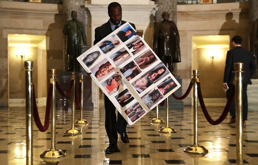 Charles Bolden, staff assistant of Rep. Robin Kelly, D-Ill., holds a poster with pictures of gun violence victims from Chicago as he walks toward the House Chamber on Wednesday in Washington, D.C.