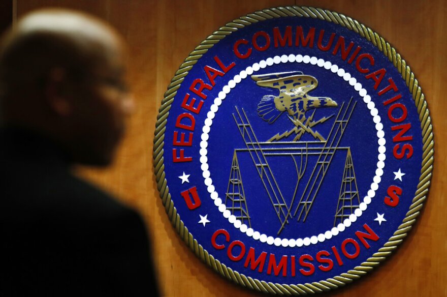 FILE- This Dec. 14, 2017, file photo, shows the seal of the Federal Communications Commission (FCC) before a meeting in Washington. Congressional leaders and a media accountability organization are urging the Federal Communications Commission to examine how policy decisions have disparately harmed Black people and other communities of color, according to a letter sent Tuesday, June 29, 2021, to the acting FCC chair. (AP Photo/Jacquelyn Martin, File)