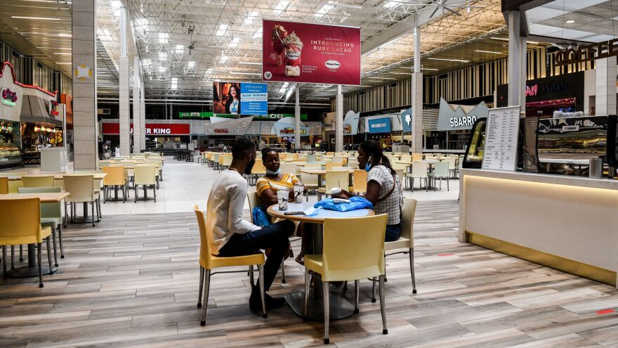 People eat in a deserted food court inside a mall west of Fort Lauderdale, Fla., Monday. U.S. states have been easing restrictions on businesses ahead of Memorial Day, the traditional start of the summer vacation and outdoor season.