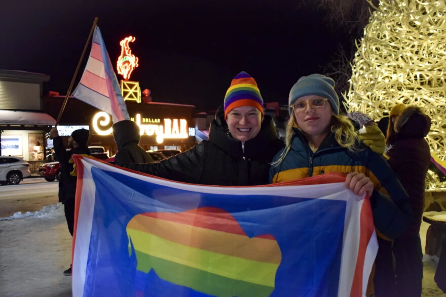 Kjera Griffith and her daughter, Augie Henrie, hold up a Wyoming state flag in the pride colors.&nbsp;