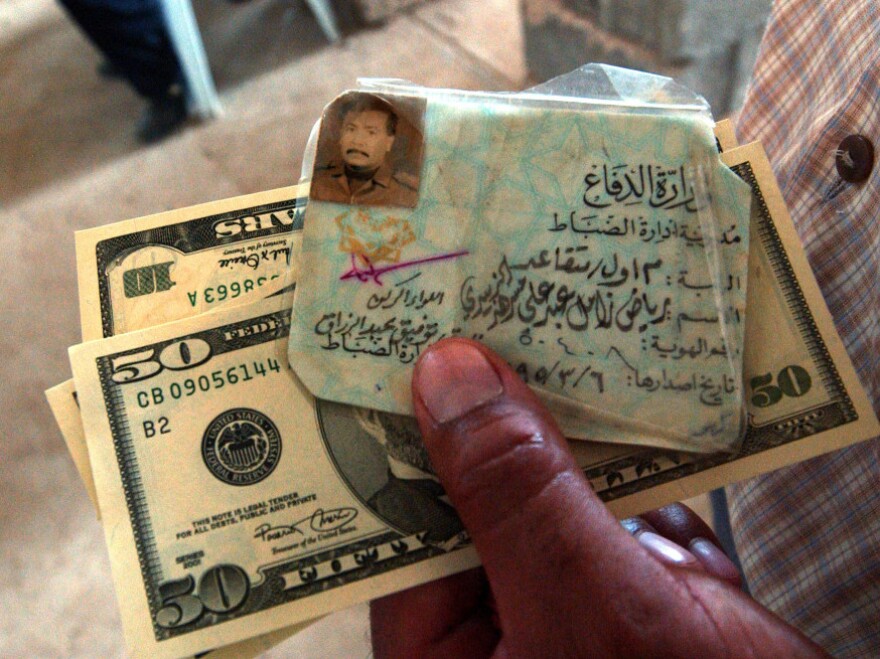 July 21, 2003: A former Iraqi Army officer holds his military I.D. and an emergency cash payment of $80.