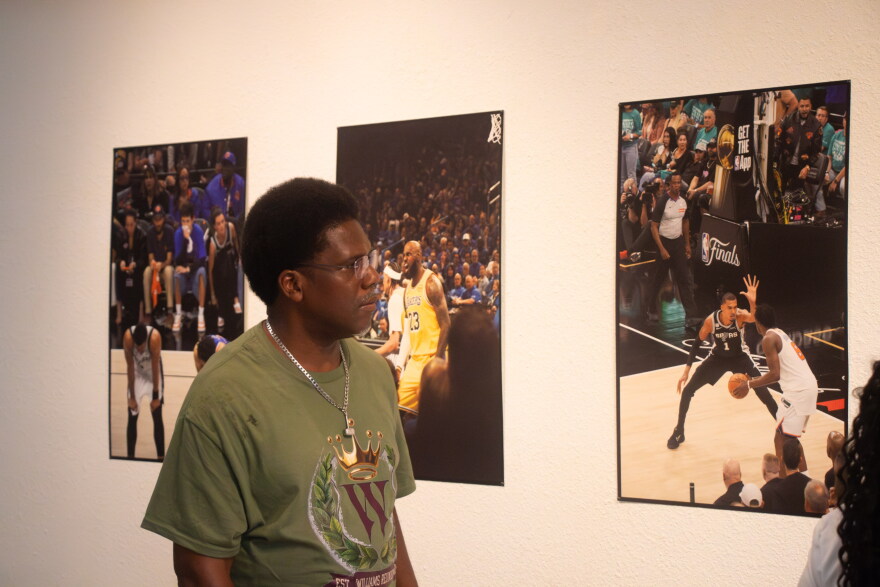 A Tubman Gallery visitor admires a collection of work by Coyia Malone. Malone was a sideline photographer during the 2026 NBA Finals.