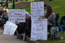 People sit in a sign holding home made signs.