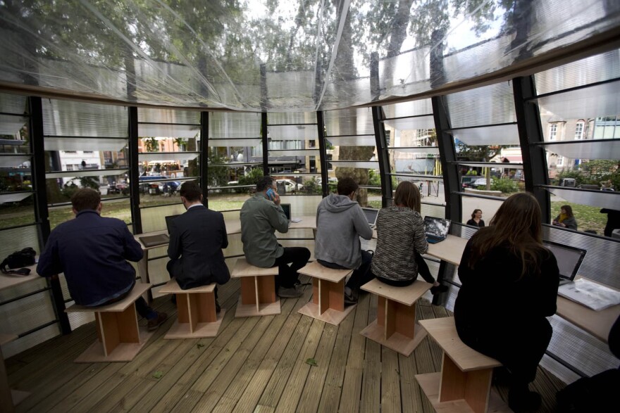 People pose for the media and work during an event to launch TREExOFFICE, a prototype pop-up tree office, in Hoxton Square, London. (Matt Dunham/AP)