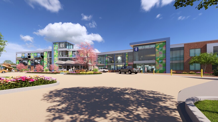 A rendering of a new women and children's hospital. The building is brightly colored and surrounded by blooming flowers.