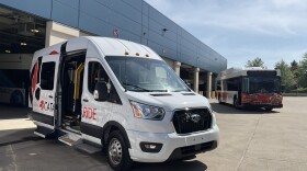 A CATARIDE vehicle and bus sit in front of a garage. 