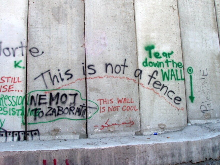 Green, red and black graffiti on a big concrete wall.