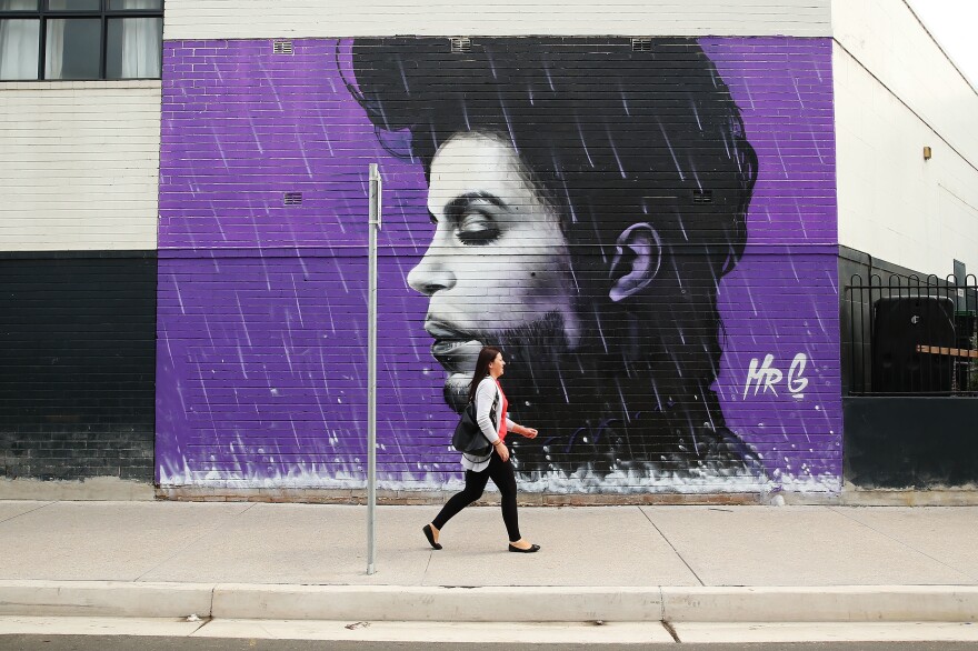 A woman walks past a mural of Prince on April 28, 2016 in Sydney, Australia.