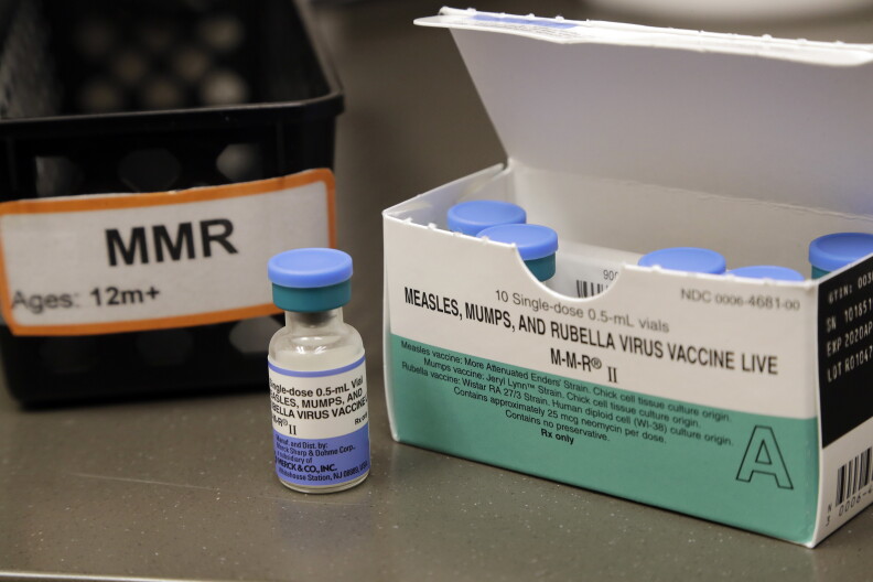 A small glass vile with a light blue cap and a box of the vials with the words "measles, mumps, and rubella virus vaccine live" 