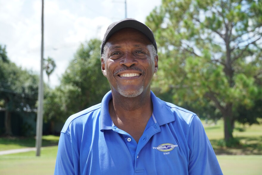 An African American wearing a blue shirt standing outside. 