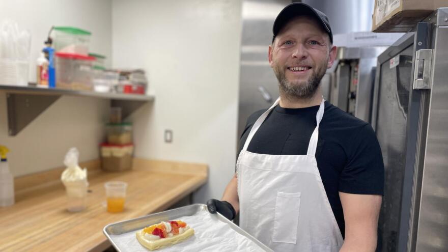 Man in apron poses with pastry o tray
