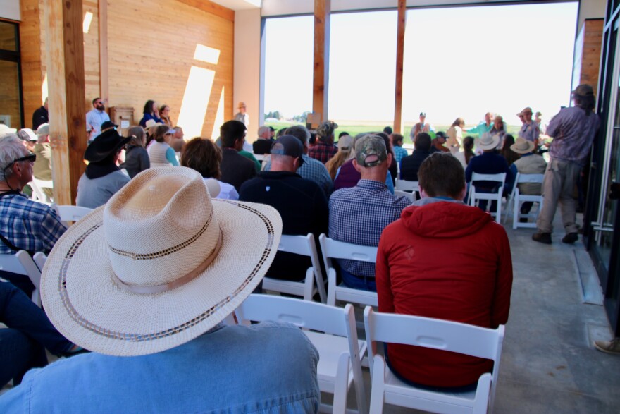 People sit in white folding chairs outside the visitors center at Minidoka National Historic Site.