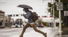 A man leaps over a large puddle on Central Avenue near the University of New Mexico on Wednesday.