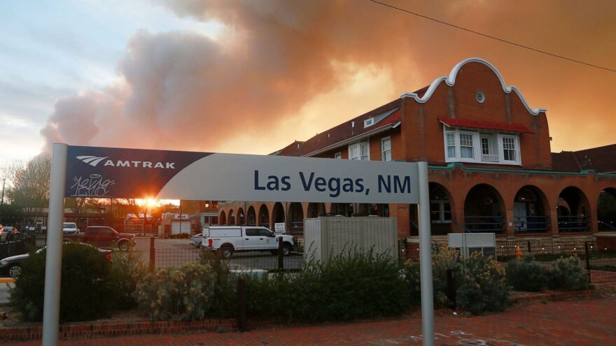 A sunset seen through a wall of wildfire smoke from the Amtrak train station in Las Vegas, N.M., on Saturday, May 7, 2022. The Castañeda Hotel, right, hosted meals for residents and firefighters this week with sponsorships from restaurants and other businesses.