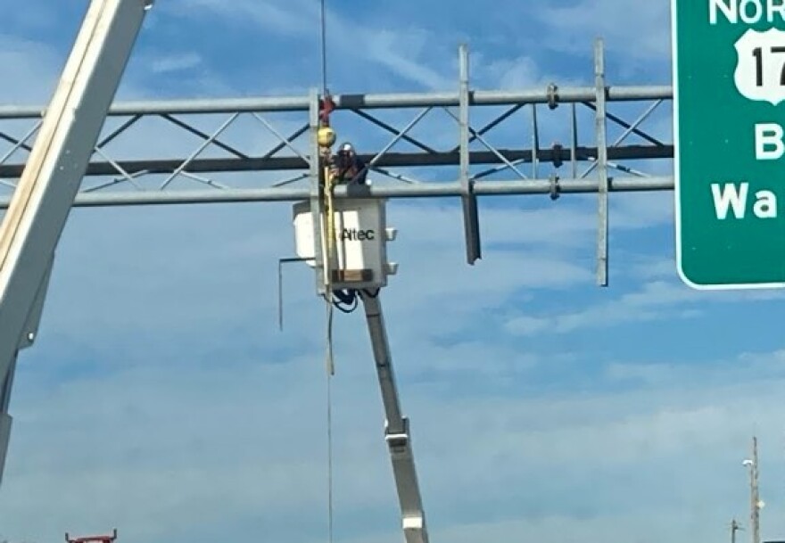 By late morning, repairs were being made to the overhead sign damaged when a garbage truck with its container elevated hit the highway marker and a pedestrian bridge.
