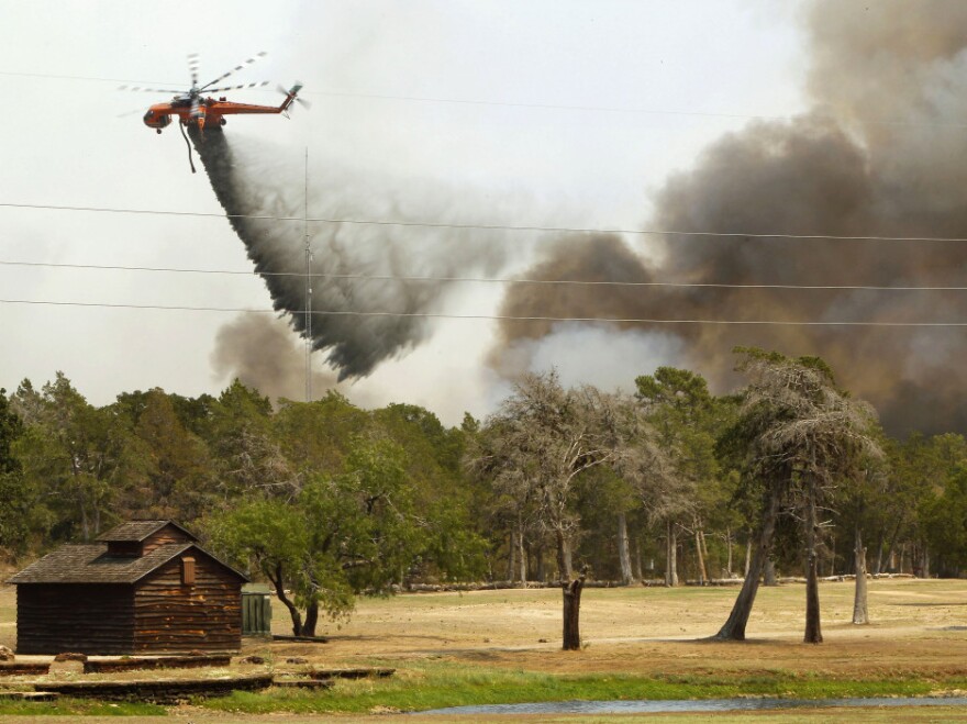 Firefighting helicopters dump water and flame retardant after loading up with water from a pond at Lost Pines Golf Club as they fight a fire in Bastrop State Park on September 6, 2011 in Bastrop, Texas.