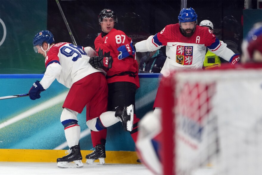 Canada's Sidney Crosby (87) is hit against the boards by Czechia's Martin Necas (98) and Radko Gudas (3) during the second period of a men's ice hockey quarterfinal game at the 2026 Winter Olympics, in Milan, Italy, Wednesday, Feb. 18, 2026. Crosby went to the dressing room after the play.