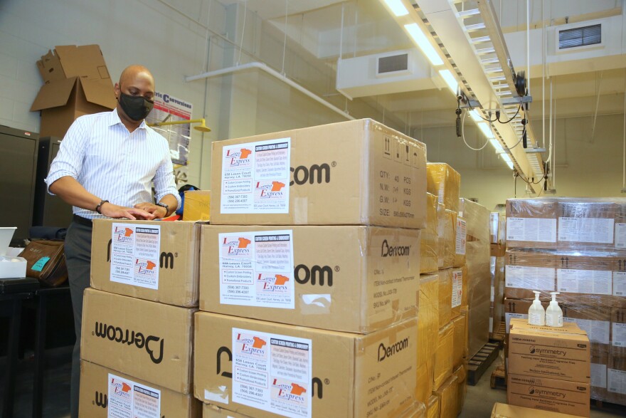 Superintendent Dr. Henderson Lewis Jr. stands next to boxes of personal protective equipment.