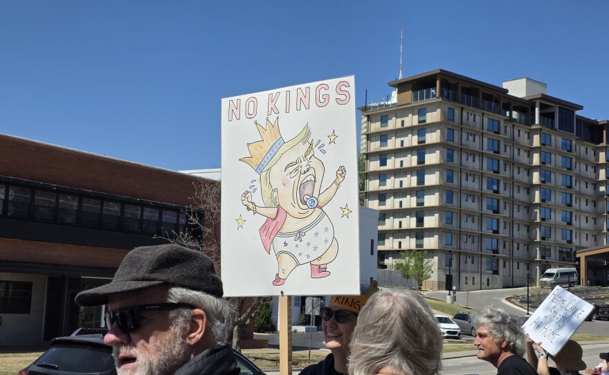 A protester holds up a sign reading "NO KINGS" with an image of President Trump as a crying baby at Tulsa's third "No Kings" rally on March 28, 2026.