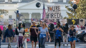People gather on Black Lives Matter Plaza on the north side of the White House where a tall metal security fence has been covered in protest signs, early Sunday, Nov. 8, 2020, the morning after incumbent President Donald Trump was defeated by his Democratic challenger, President-elect Joe Biden. 