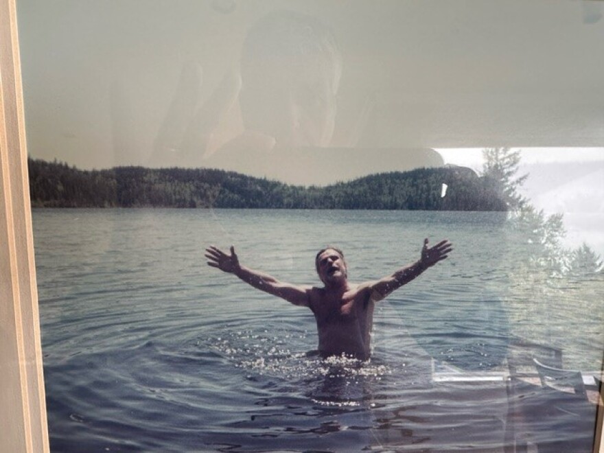 A man stands in a lake with arms outstretched.