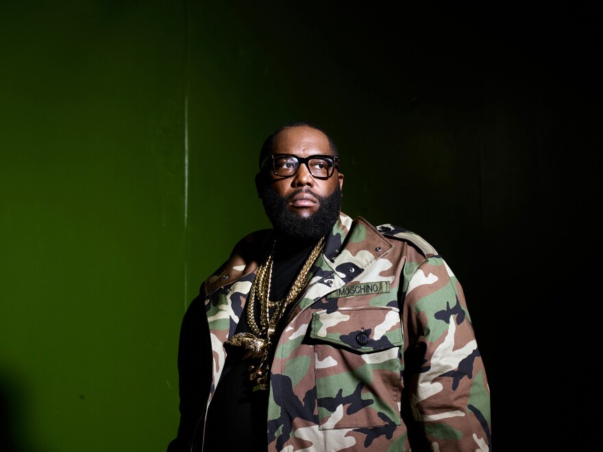 A man wearing glasses and a camouflage jacket looks intently at something out of frame.