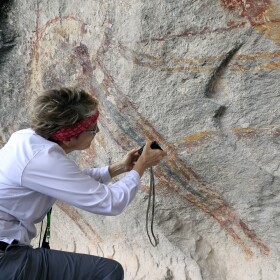 Carolyn Boyd examines the painting sequence of a Pecos River style figure at Fate Bell Shelter in Seminole Canyon State Park and Historic Site.