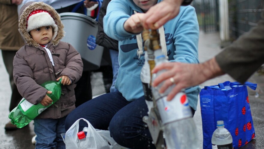 A young child held an empty bottle as people queued to recieve water from a  tap in Belfast on Wednesday.