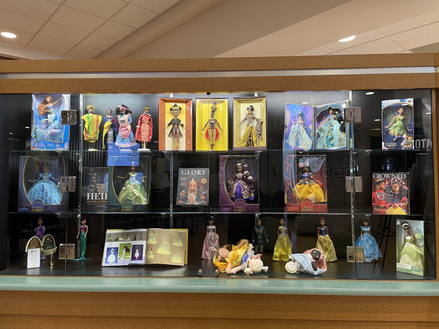 A case in the exhibit is pictured. It includes Black dolls from Ariel in Disney's The Little Mermaid, through to dolls representing African and Caribbean countries