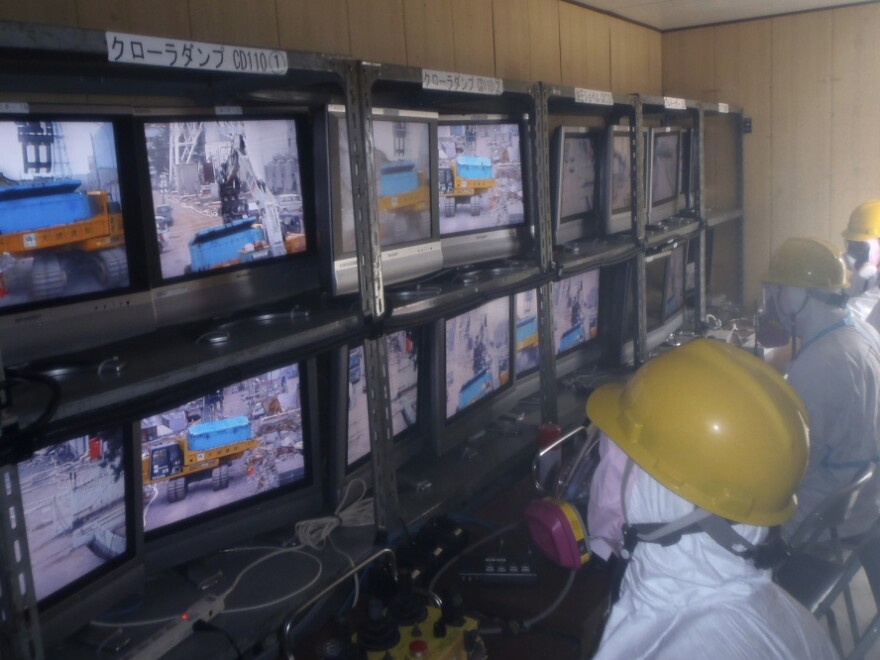Workers operate remote-controlled rubble-removing equipment at the Fukushima Dai-ichi nuclear complex. Though robotic machines will be able to clear some of the larger debris from the facility, some people will most likely be needed to work inside the reactor buildings.