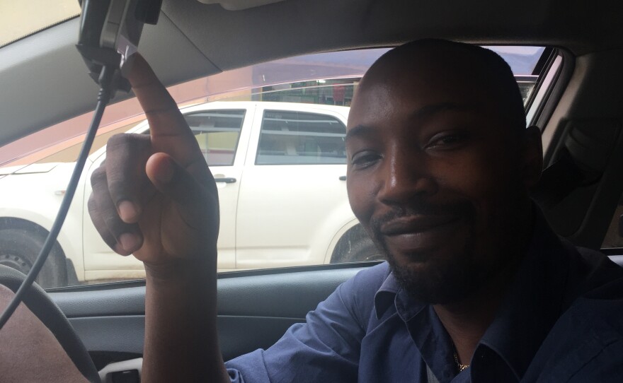 One of Uber's Nairobi drivers, Jackson Kamau, points proudly to an iPhone that shows his high rating.