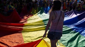 Parade participants hold a large Pride flag as they wait for the parade to begin.