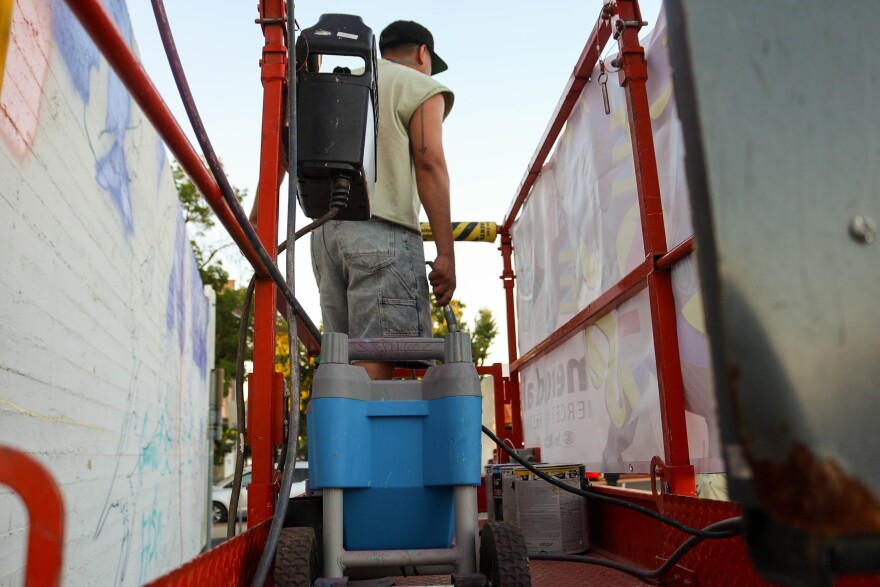 Joel Aguilar looks out over the riser in between painting onto the wall.