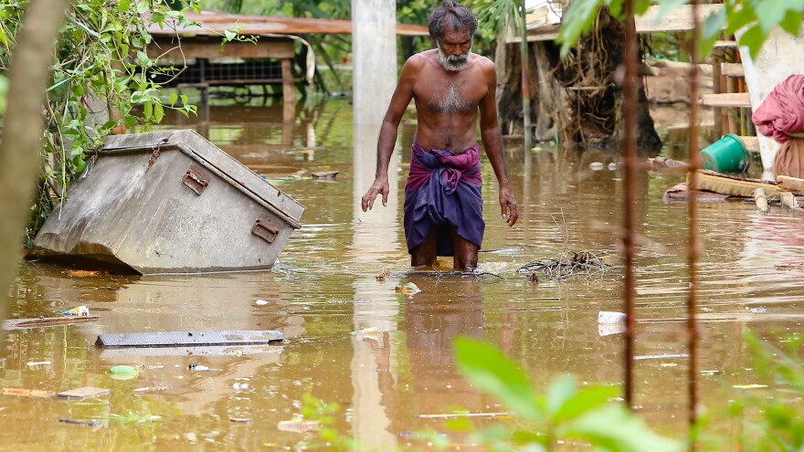 A Sri Lankan man walks through floodwaters in Kaduwela, Sri Lanka, on Friday. More than 90 people were reported dead after unusually heavy rains triggered floods and mudslides in Sri Lanka.