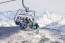 Multiple people sit on a ski lift.