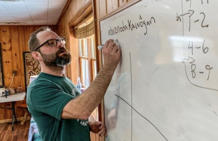 A person writes "abaznodakaw8gan" on a white board.