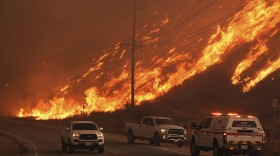 Firefighters monitor flames caused by the Hughes Fire along Castaic Lake in Castaic, Calif.