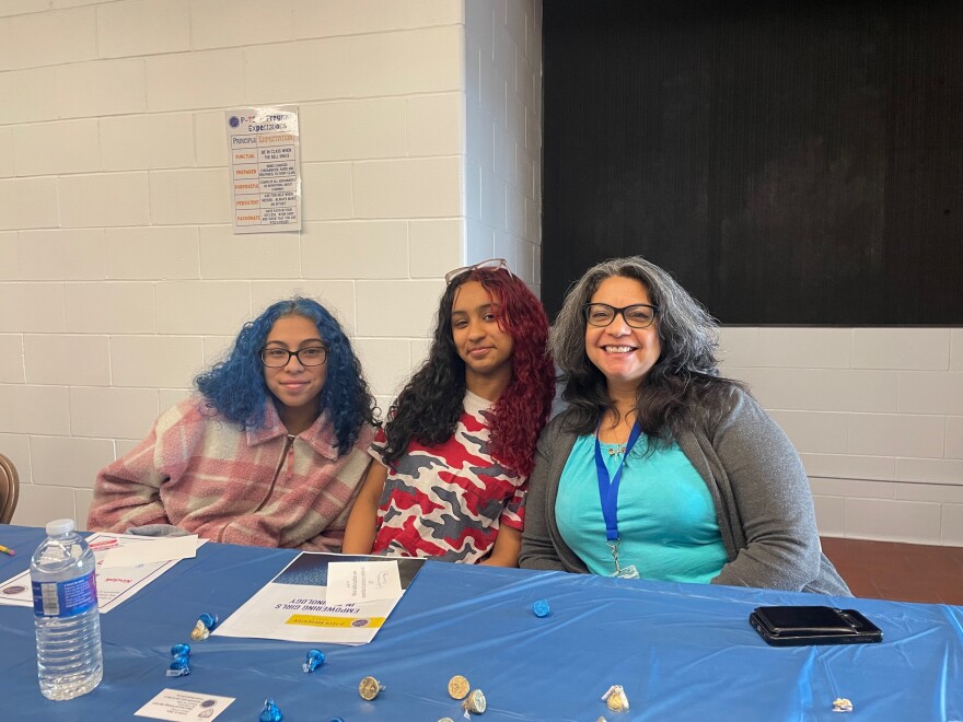 Two students sit with a guest speaker at a table in a school setting