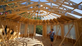 Workers build a home Tuesday, Sept. 19, 2023, in Marshall, N.C. Climate change is increasing billion-dollar disasters, many of them from intensifying hurricanes. Housing developers are now building homes, some of them round, that can resist hurricane-force winds and at the same time generate much less of the emissions that contribute to climate change. 