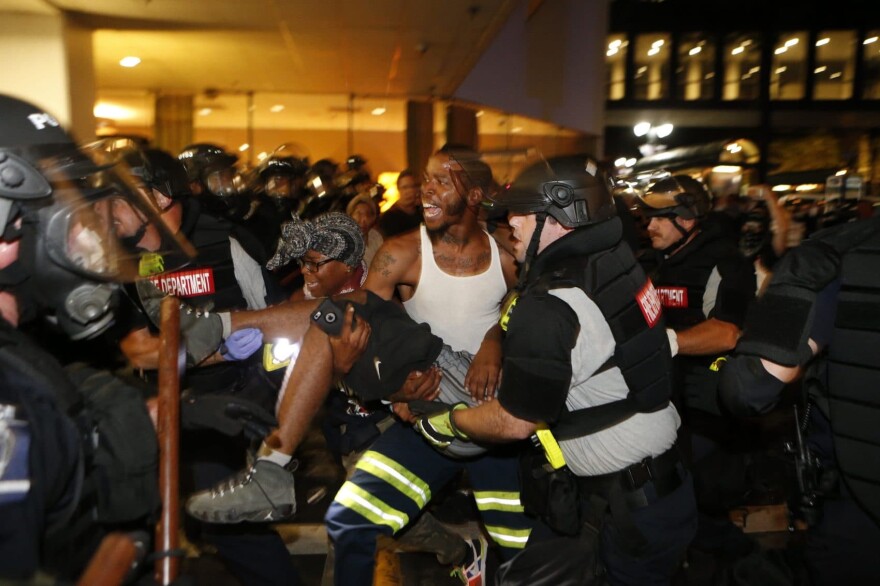 Police and protesters carry a seriously wounded protester into the parking area of the the Omni Hotel during a march to protest the death of Keith Scott Sept. 21, 2016 in Charlotte, N.C. (Brian Blanco/Getty Images)