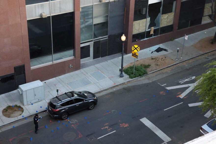 An investigator with the Sacramento Police Department takes a photo of the scene of a shooting near 10th and K streets Sunday, April 3, 2022.