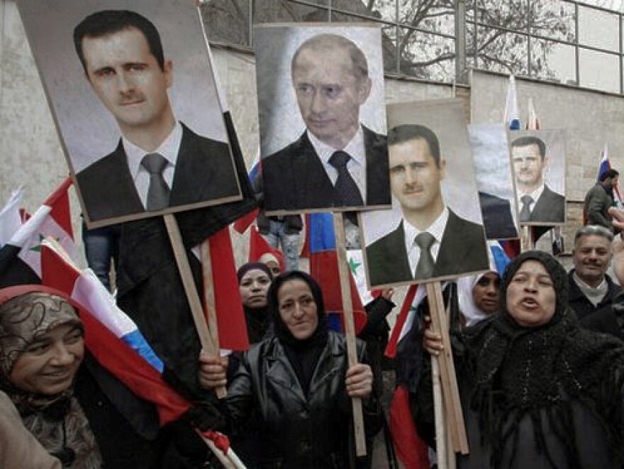 Syrian protesters hold signs with the faces of president Bashar al-Assad and Russian President Vladimir Putin in Damascus - March 4, 2012