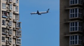 A Cathay Pacific airliner flies past residential buildings as it prepares to land at the Beijing Capital International Airport, in Beijing, Monday, Dec. 1, 2025. (AP Photo/Andy Wong)