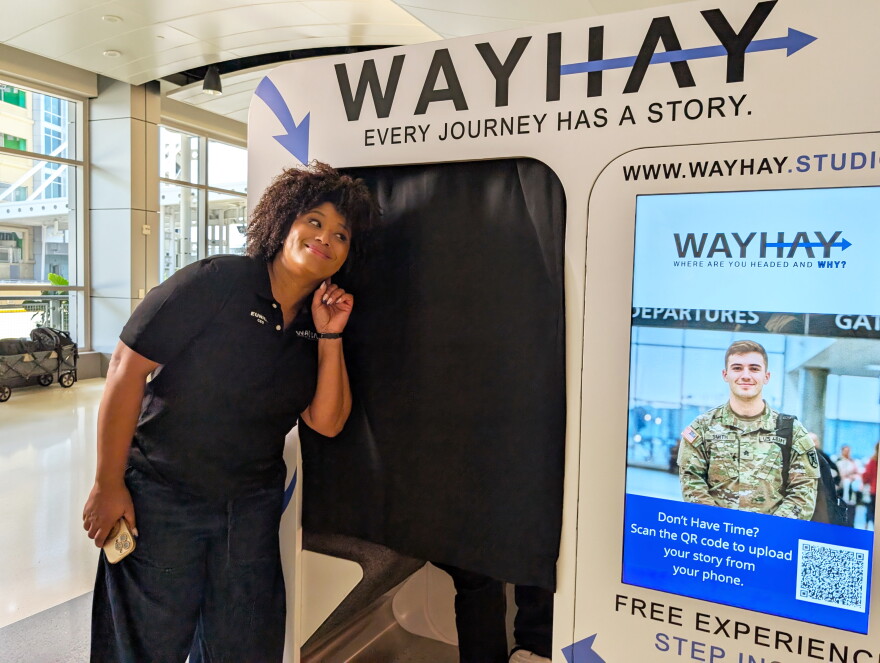 Eunice Elliott stands in front of the WAYHAY booth at the Birmingham airport.