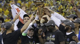 Golden State Warriors players, coaches and owners hold up the Larry O'Brien NBA Championship Trophy after Game 5 of basketball's NBA Finals between the Warriors and the Cleveland Cavaliers in Oakland, Calif., Monday, June 12, 2017. (Marcio Jose Sanchez/AP)