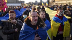 A demonstrator cries listening a national anthem as other rally with Ukrainian national flags in the center of Kharkiv, Ukraine's second-largest city, Saturday, Feb. 5, 2022. (Evgeniy Maloletka/AP Photo)