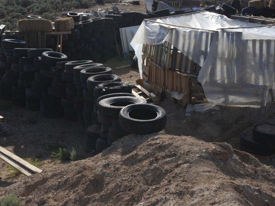 Tires form a wall at the squalid makeshift living compound where five adults were arrested on child abuse charges and the remains of a boy were found.